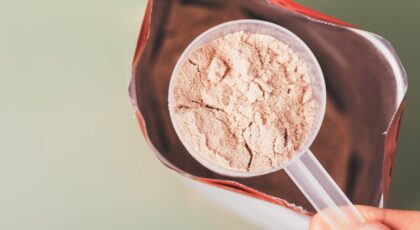 Imagem de uma pessoa pegando um scoop de whey protein do pacote