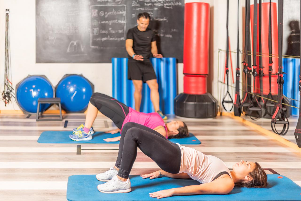 Duas mulheres fazendo ponte de exercício físico no colchonete.