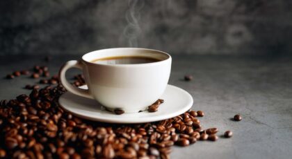 Imagem de uma xícara de café com grãos em volta