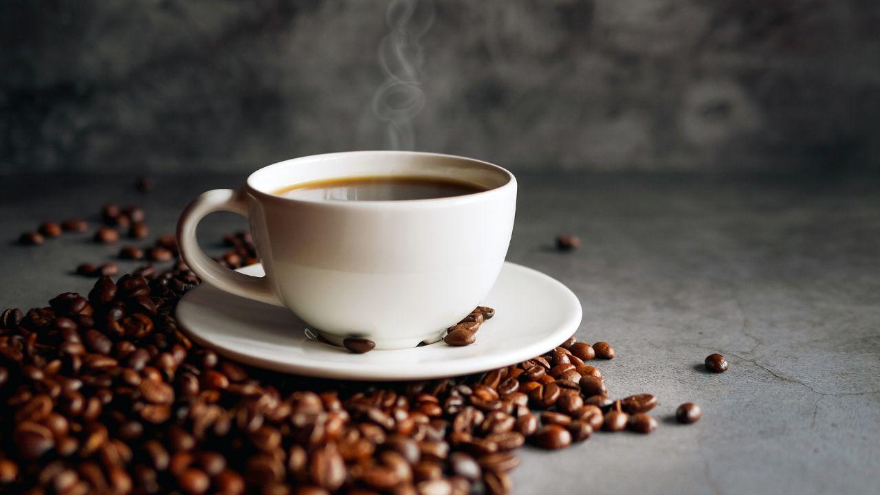 Imagem de uma xícara de café com grãos em volta