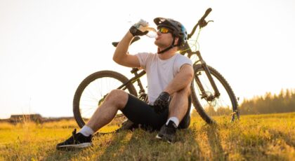 Homem sentado na grama com uma bicicleta ao lado.