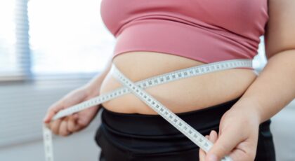 Foto mostra uma barriga de mulher com fita métrica em volta.