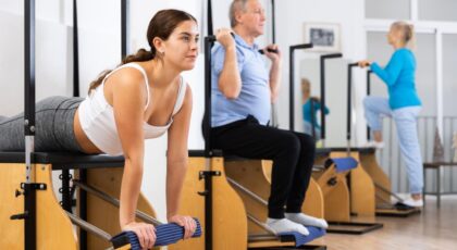 Foto mostra pessoas fazendo pilates em equipamentos.