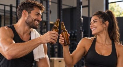 Imagem de um homem e uma mulher brindando com garrafas de cerveja após o treino
