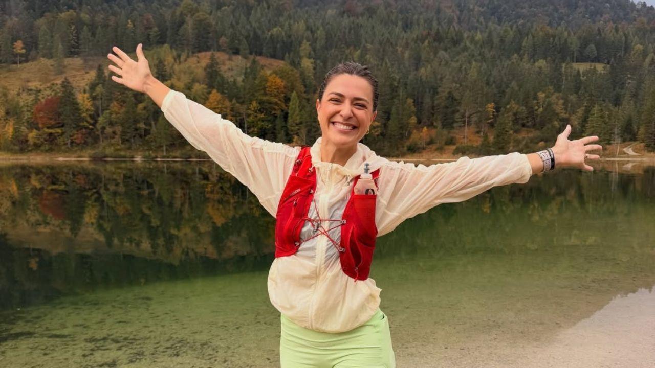 Imagem de Bruna Ianhez com os braços abertos em uma trilha